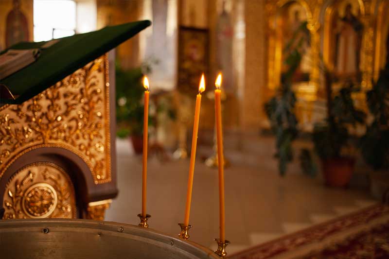 Three candles are burning inside an Orthodox church in Greece
