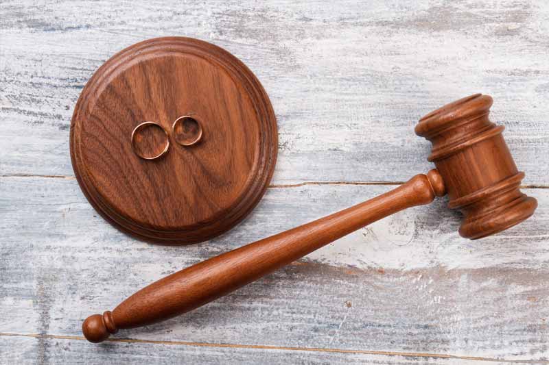 Concetto di divorzio: Fedi nuziali e martelletto di legno del giudice visti dall'alto
