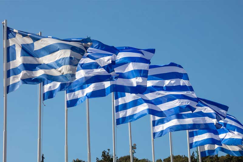 Greek national flags waving on clear blue sky